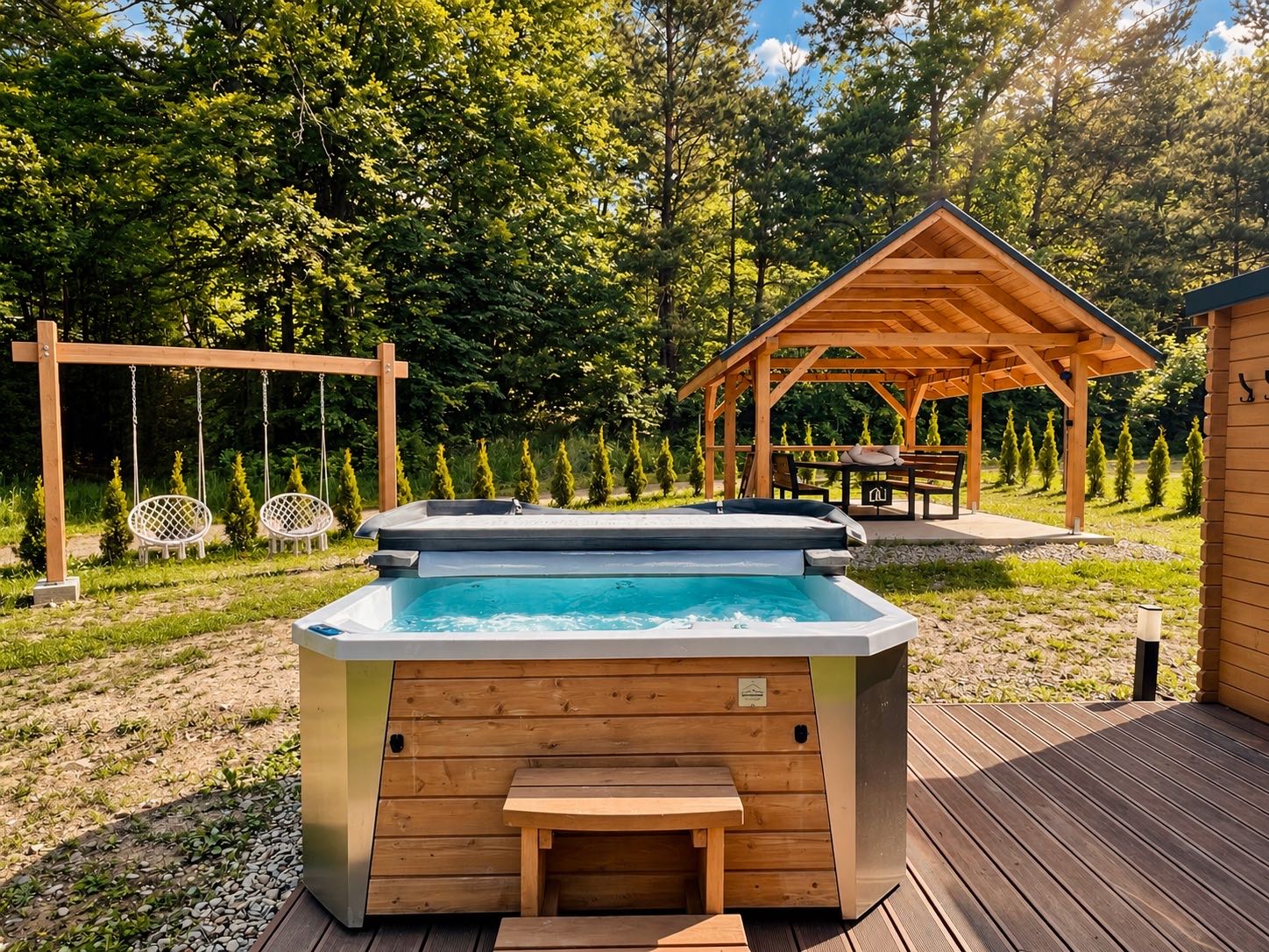 Jacuzzi obok altany latem, w tle zielone wzgórza